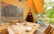 Tavolo in legno con ciotole davanti alla tenda safari Cabane al Bivouac nature in Francia.