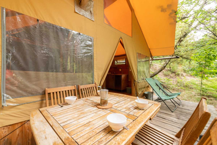 Wooden outdoor dining set on the deck of a Cabane safari tent at Bivouac nature in France.