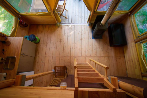 Interieur van de Cabane safaritent bij Bivouac nature in Frankrijk, met houten vloer en keukenblok.