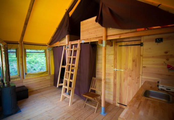 Innenraum eines Safari-Zeltes namens Cabane bei Bivouac nature in Frankreich mit Holzboden und Schlafboden.