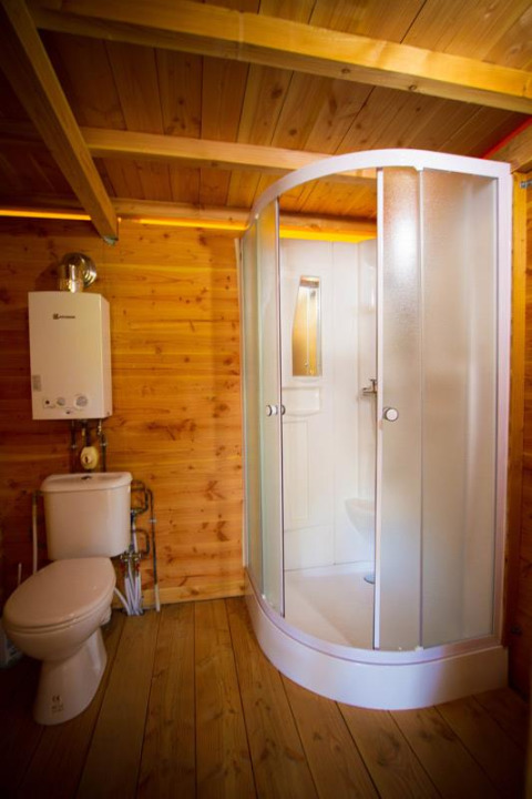 Badeværelse i træ med brusekabine og toilet på en safarihytte kaldet Cabane på Bivouac nature, Frankrig.