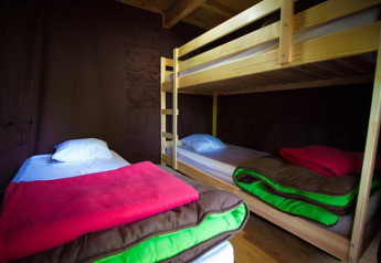 Vue intérieure de la tente safari Cabane au Bivouac Nature en France avec lits simples et lits superposés.