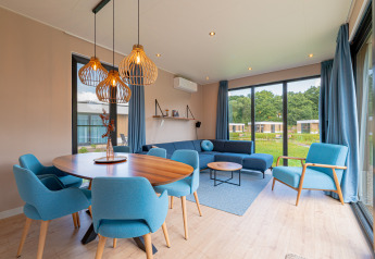 Salón y comedor moderno en la Water lodge 6 Deluxe con asientos azules en Hofparken Wiltershaar, Países Bajos.