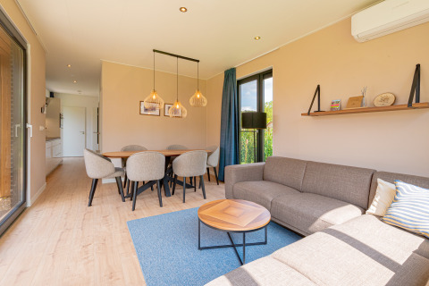 Gezellig interieur van Parklodge 6 met ruime eethoek, zithoek, houten vloer en grote ramen.
