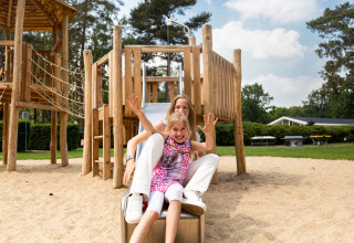 Kind en volwassene glijden samen van een glijbaan op de speeltuin van Holiday Park Gelloo in Gelderland.