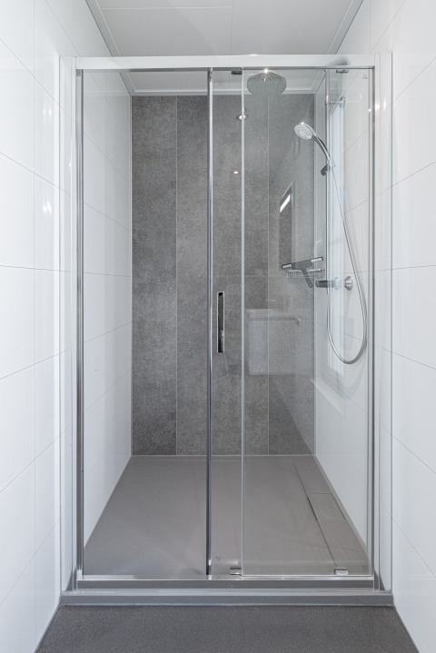 Moderne douchecabine met glazen deuren en grijze tegels in Parklodge 6, Hofparken Wiltershaar.