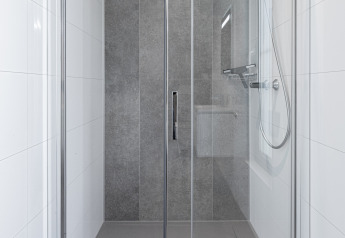 Moderna cabina de ducha con puertas de cristal y azulejos grises en Parklodge 6, Hofparken Wiltershaar.