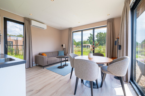 Lichte, moderne leefruimte van Water lodge 2 Deluxe met sauna, hot tub en natuurzicht bij Hofparken Wiltershaar.