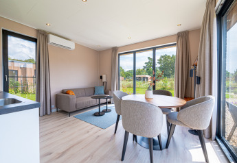 Lichte, moderne leefruimte van Water lodge 2 Deluxe met sauna, hot tub en natuurzicht bij Hofparken Wiltershaar.