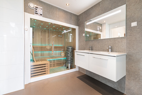 Baño moderno con lavabo doble, gran espejo y sauna acristalada en Water lodge 2 Deluxe, Países Bajos.