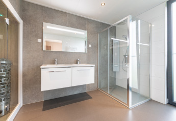 Modern bathroom in Water lodge 2 Deluxe at Hofparken Wiltershaar featuring double sink, shower, and sauna.