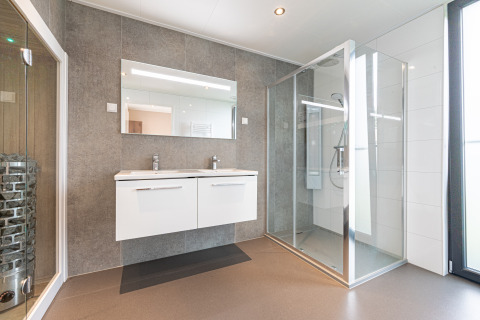 Baño moderno de Water lodge 2 Deluxe con lavabo doble, ducha y sauna en Hofparken Wiltershaar, Países Bajos.