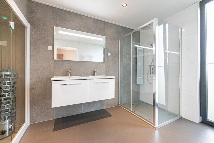Baño moderno de Water lodge 2 Deluxe con lavabo doble, ducha y sauna en Hofparken Wiltershaar, Países Bajos.