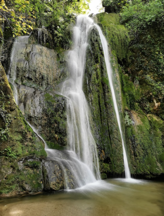 Superbe cascade entourée de verdure près de BAGE DOMMARTIN, en Auvergne-Rhône-Alpes, France.