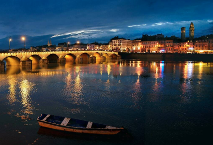 Scène nocturne d’un pont illuminé et de la ville reflétée sur la rivière près de BAGE DOMMARTIN, Auvergne-Rhône-Alpes.
