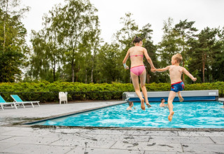 Les enfants sautent dans la piscine extérieure - Recreatiepark 't Gelloo - Ede, Gelderland, Pays-Bas