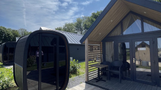 Photo extérieure de la Berg Lodge avec sauna moderne par temps ensoleillé sous un ciel bleu.