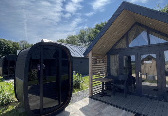 Outdoor photo of Berg Lodge featuring a modern sauna unit and sunny weather under a blue sky.