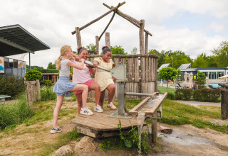 Tre bambini giocano con una pompa d’acqua nel parco giochi all’aperto di Holiday park Ackersate, Gelderland.