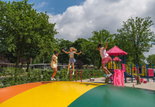 Children jumping on a colorful air cushion in the playground at Holiday park Ackersate, Gelderland, Netherlands.
