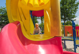 Bambino piccolo che gioca su uno scivolo colorato nel parco giochi di Holiday park Ackersate, Gelderland, Paesi Bassi.