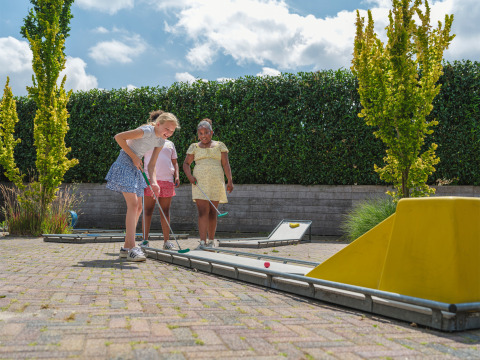 Niños juegan al minigolf al aire libre en un día soleado en Holiday park Ackersate, Gelderland, Países Bajos.