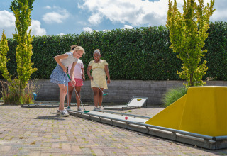 Kinder spielen im Freien Minigolf bei Sonnenschein im Holiday Park Ackersate, Gelderland, Niederlande.