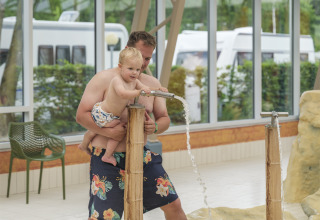 Père aidant son jeune enfant à jouer avec une fontaine d'eau au Holiday park Ackersate, Gelderland, Pays-Bas.