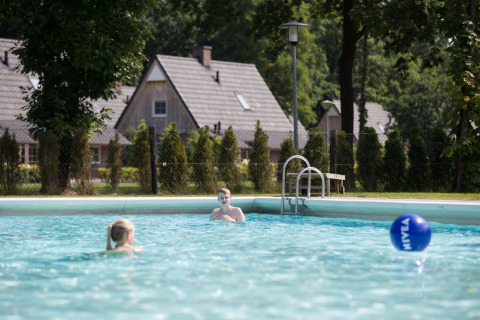 Twee kinderen zwemmen in een buitenzwembad bij Hof van Salland vakantiepark in Overijssel, Nederland.
