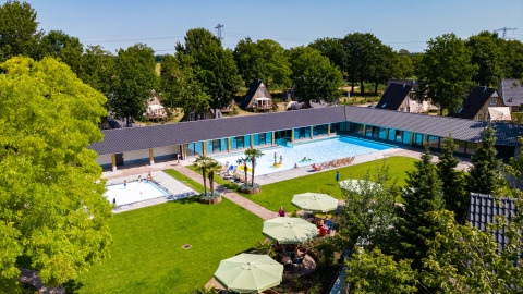 Gezicht op het zwembad en vakantiehuisjes van Hof van Salland, een vakantiepark in Overijssel, Nederland.