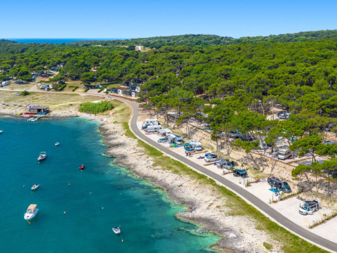 Camping Arena Stupice holiday park in Istria, Croatia, with campers by the sea and boats on blue water.