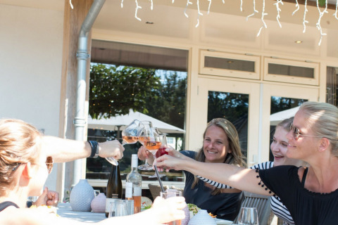 Vier vrouwen proosten buiten aan een tafel bij Hof van Salland, een vakantiepark in Overijssel, Nederland.