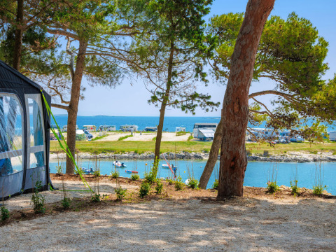 View from a campsite at Arena Stupice in Istria, Croatia, with sea, campervans and pine trees.