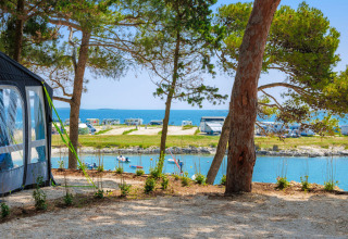 View from a campsite at Arena Stupice in Istria, Croatia, with sea, campervans and pine trees.