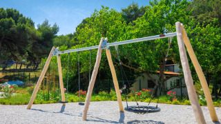 Legeplads med gyngestativ omgivet af grønne træer på Camping Arena Stupice i Istrien, Kroatien.