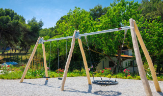 Legeplads med gyngestativ omgivet af grønne træer på Camping Arena Stupice i Istrien, Kroatien.