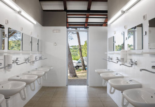 Baño comunitario con varios lavabos y espejos en Camping Arena Stupice, parque vacacional en Istria, Croacia.