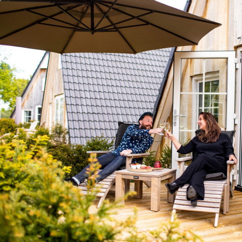Koppel geniet van een drankje op het terras van hun vakantiehuis bij Hof van Salland, Overijssel.