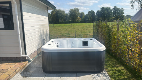 Bubbelbad naast Wilbrink chalet bij Vakantiepark De Boshoek in Nederland, met uitzicht op het weiland.