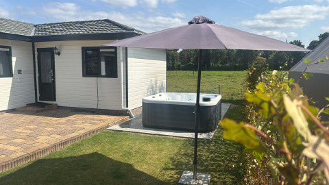 Buiten bij Wilbrink chalet op Holiday park De Boshoek in Nederland met terras, jacuzzi en parasol.