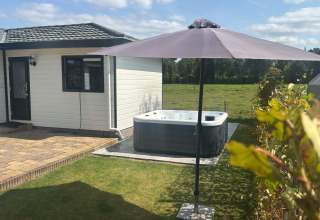 Buiten bij Wilbrink chalet op Holiday park De Boshoek in Nederland met terras, jacuzzi en parasol.