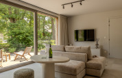 Bright living room in Suite at Woodz Lodges, Belgium, featuring a modern sofa, terrace, and garden view.