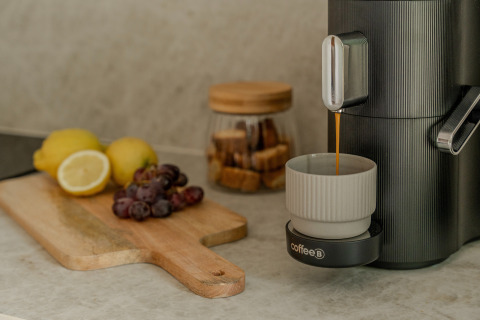 Een koffiemachine serveert koffie in een tas, met fruit en suiker op het aanrecht in een Belgische lodge.