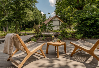 Dos sillas de madera y una mesa en una terraza rodeada de árboles en Suite at Woodz Lodges, Bélgica.