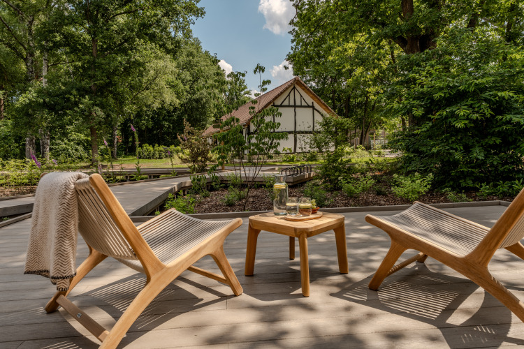 Dos sillas de madera y una mesa en una terraza rodeada de árboles en Suite at Woodz Lodges, Bélgica.