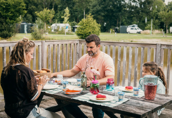 Famiglia fa colazione all'aperto vicino a una tenda safari di lusso sul lungomare di Sallandshoeve.