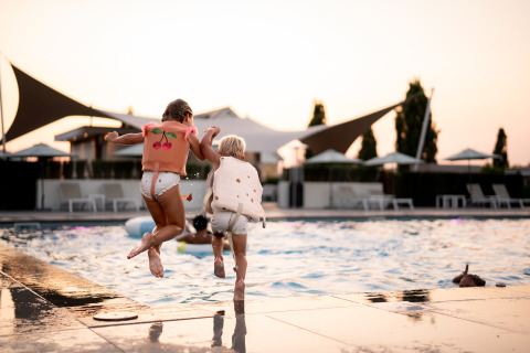 To børn iført redningsveste hopper i poolen ved Berg Lodge - Sauna på Resort Mooi Bemelen, Nederlandene.