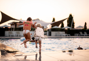 Two children wearing life vests jump into the pool at Berg Lodge - Sauna at Resort Mooi Bemelen, Netherlands.