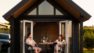Zwei Personen genießen die Terrasse der Berg Lodge - Sauna im Resort Mooi Bemelen in den Niederlanden.
