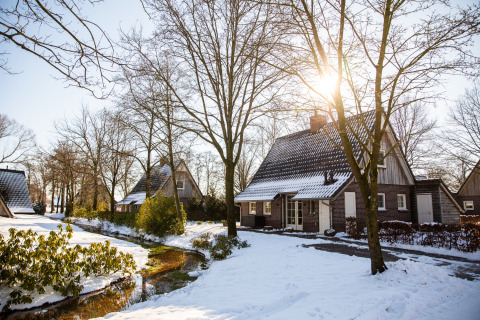 Vakantiehuisjes in Hof van Salland, Overijssel, Nederland, bedekt met sneeuw op een zonnige winterdag.
